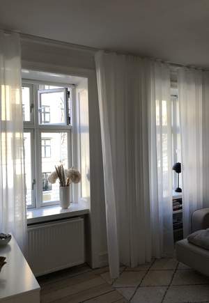 Vita genomsiktliga gardiner i vardagsrummet